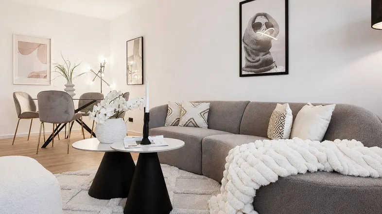 Moderner Wohn-Essbereich mit stilvollem Sofa, Esstisch und minimalistischer Dekoration.