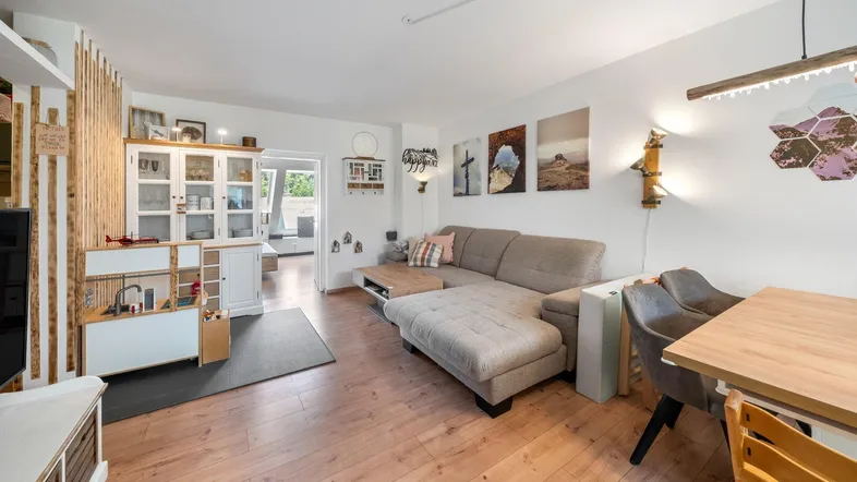 Helles Wohn- und Esszimmer mit Holzboden, bequemer Couch und Essbereich.