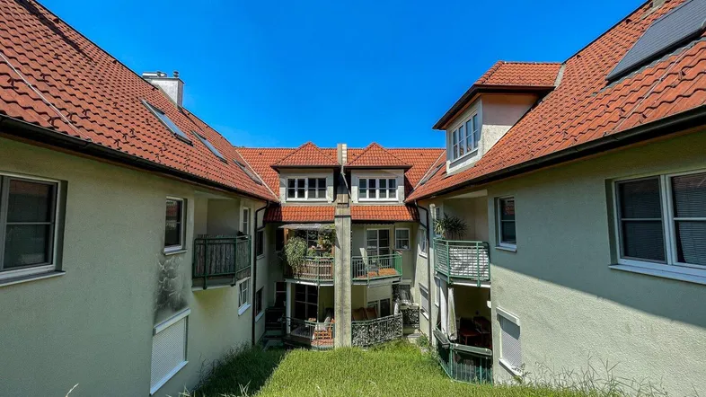 Innenhof zwischen Wohngebäuden mit begrünten Flächen und Balkonen.
