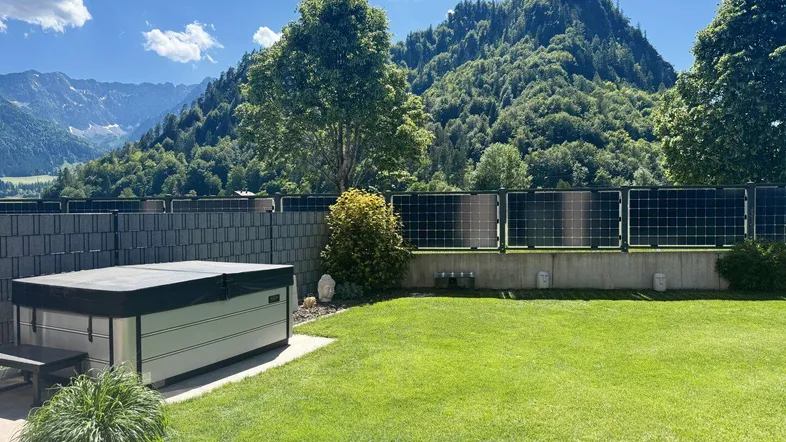 Geräumiger Gartenbereich mit Whirlpool, Rasenfläche und beeindruckendem Bergblick.
