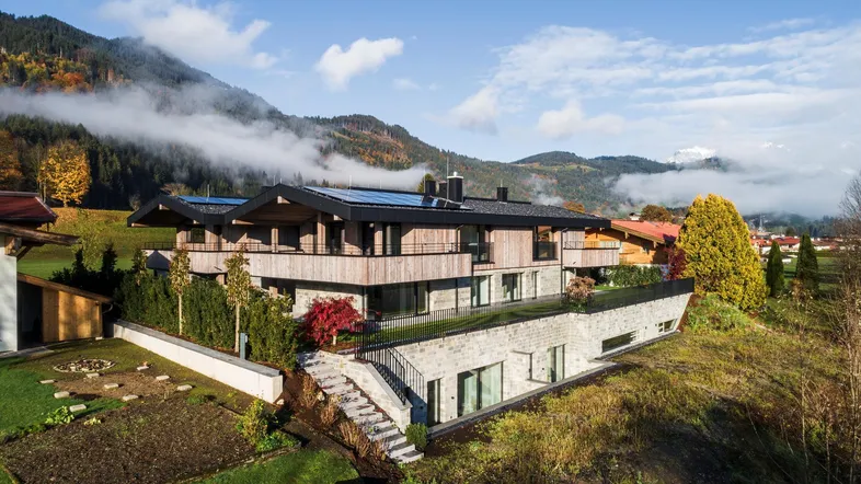 Modernes Wohnhaus in alpiner Umgebung mit Photovoltaikanlage auf dem Dach und Bergblick.