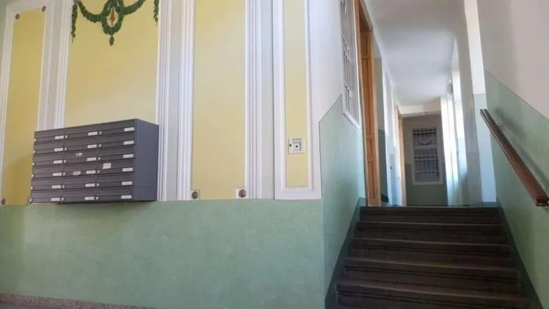 Historisches Treppenhaus mit verzierten Wänden, Briefkästen und Zugang zu den oberen Etagen.