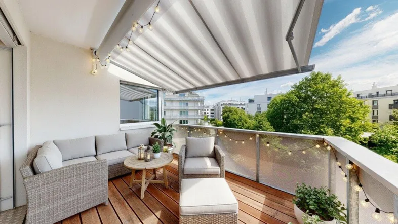Gemütlicher Balkon mit Holzboden, Markise und bequemen Outdoor-Möbeln, ideal zum Entspannen.