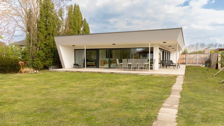 Moderne Architektur mit großzügiger Terrasse, weitläufigem Rasen und viel Grünfläche.