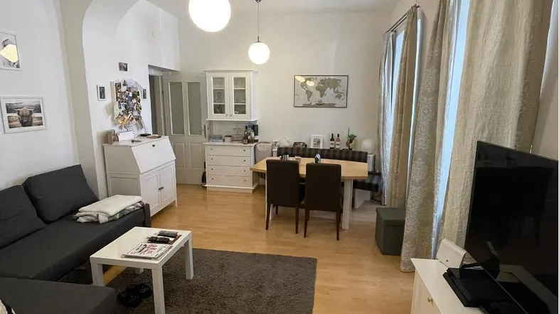 Helles Wohn- und Esszimmer mit Parkettboden, modernen Möbeln und dekorativen Elementen.