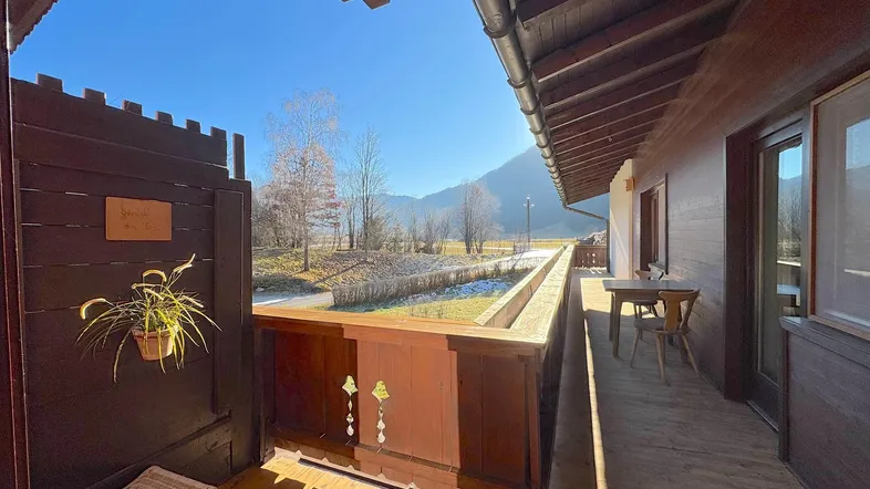 Geräumiger Holzbalkon mit traditionellem Geländer und weitem Blick auf die umliegende Berglandschaft.