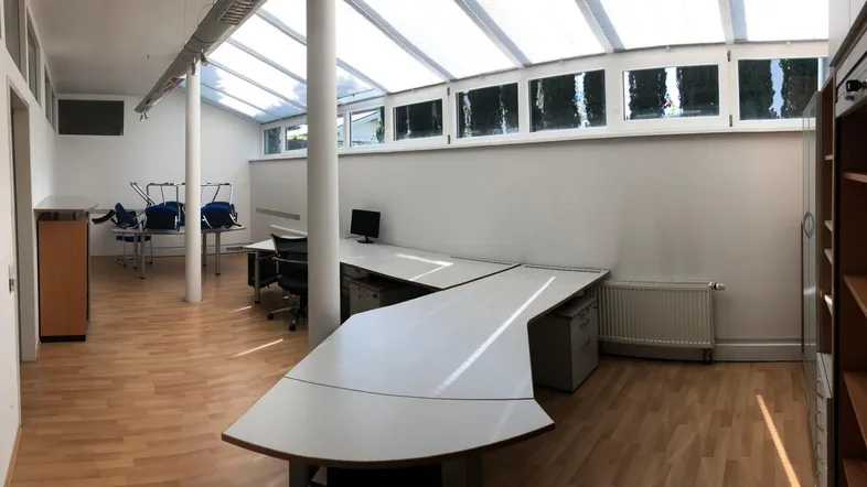 Geräumiges Büro mit großen Fenstern, viel Tageslicht und Holzfußboden, ideal für produktives Arbeiten.