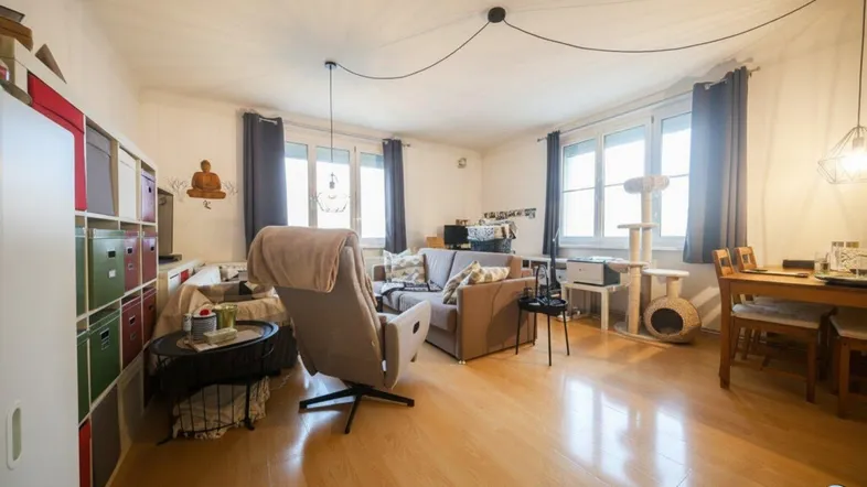 Helles Wohn- und Esszimmer mit Parkettboden, großen Fenstern und gemütlicher Einrichtung.