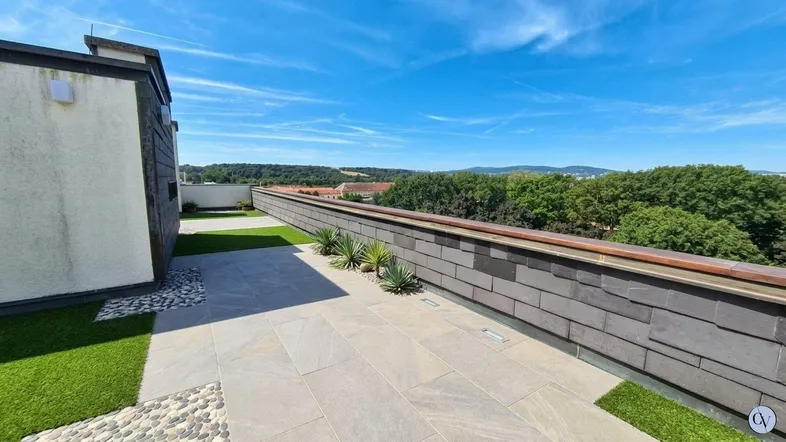 Geräumige Dachterrasse mit Kunstrasen, Steinplatten und weitem Blick ins Grüne.