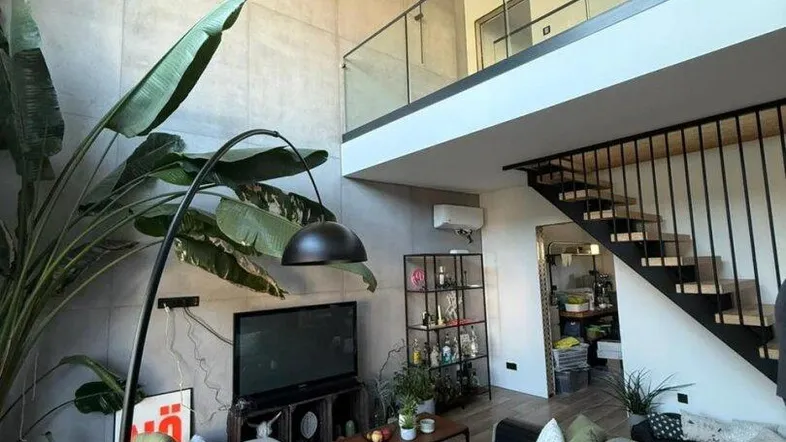 Geräumiges Wohnzimmer mit hoher Decke, moderner Einrichtung und Zugang zu einer Galerie.