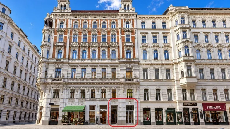 Historisches Gebäude mit mehreren Etagen und Geschäften im Erdgeschoss an einer belebten Straße.