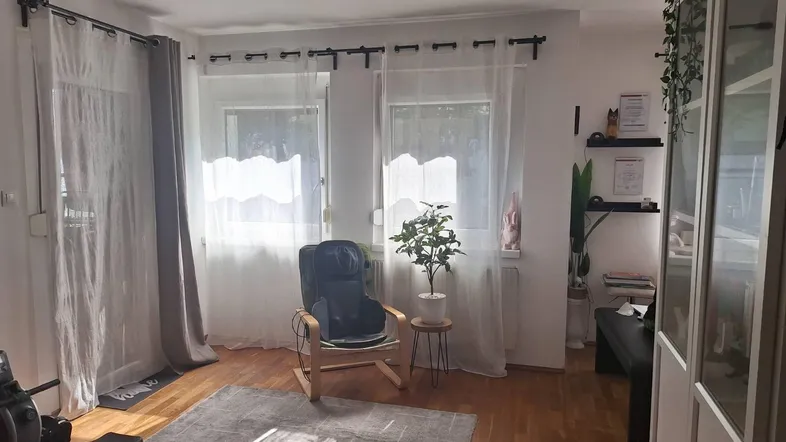 Helles Wohnzimmer mit Holzboden, einem Sessel und Fitnessgerät, durchflutet von Tageslicht.