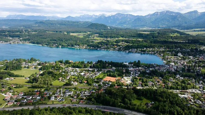 Panoramablick aus der Vogelperspektive auf einen See, eine Stadt und die umliegende Berglandschaft.