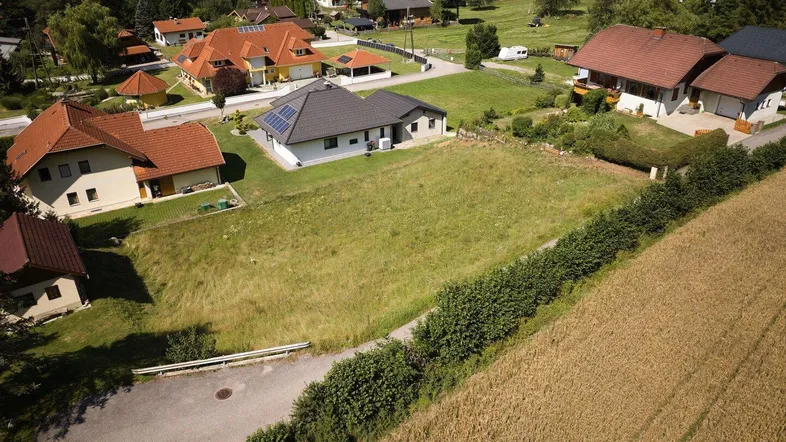 Luftaufnahme eines Wohngebiets mit großem unbebautem Grundstück und umliegenden Häusern.