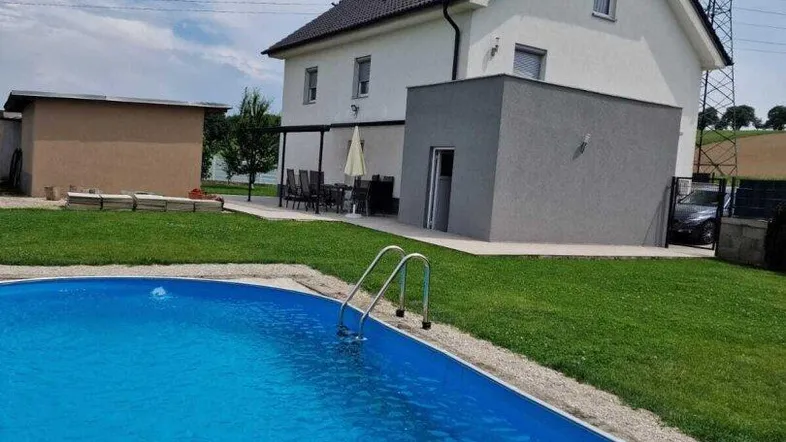 Modernes Haus mit Swimmingpool und Terrasse im Garten unter blauem Himmel.