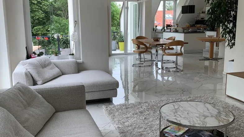 Helles, offenes Wohn- und Esszimmer mit modernen Möbeln, glänzenden Fliesen und Zugang zum Balkon.