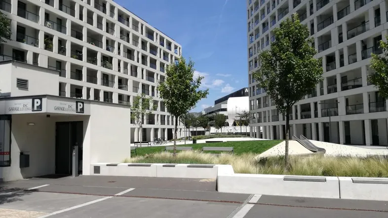 Moderne Wohngebäude mit Tiefgaragenzufahrt und begrüntem Innenhofbereich.