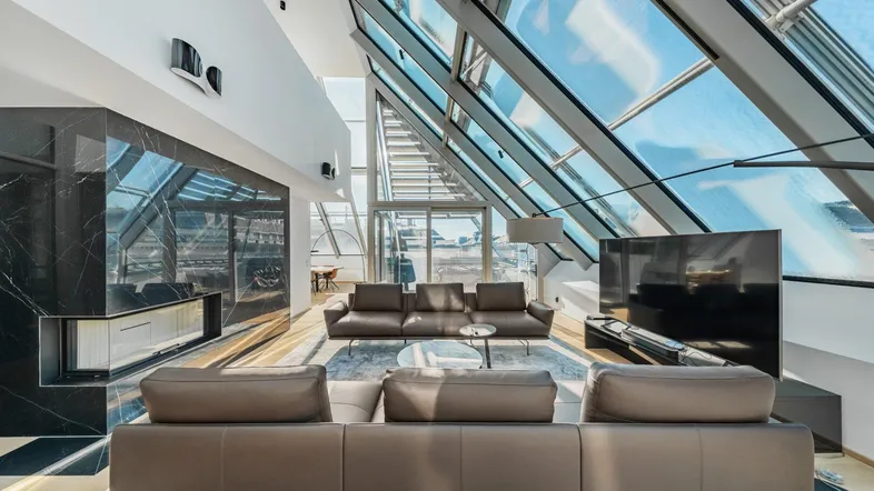 Großzügiges, lichtdurchflutetes Wohnzimmer mit hohen Decken, Dachfenstern und modernem Interieur.