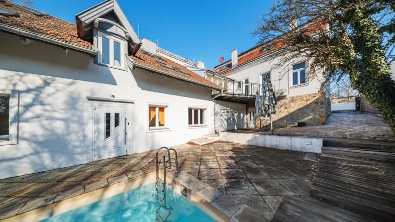 Hinterhofbereich mit einem kleinen Pool, Steinfliesen und einer Holzterrasse.