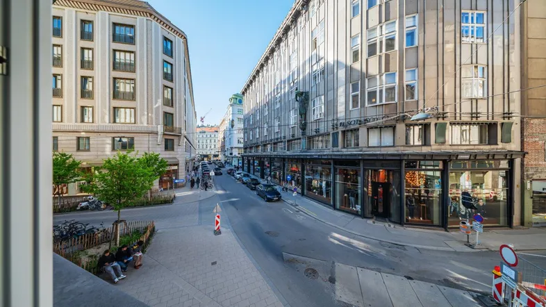 Blick auf eine belebte Stadtstraße mit modernen und klassischen Gebäudefassaden.