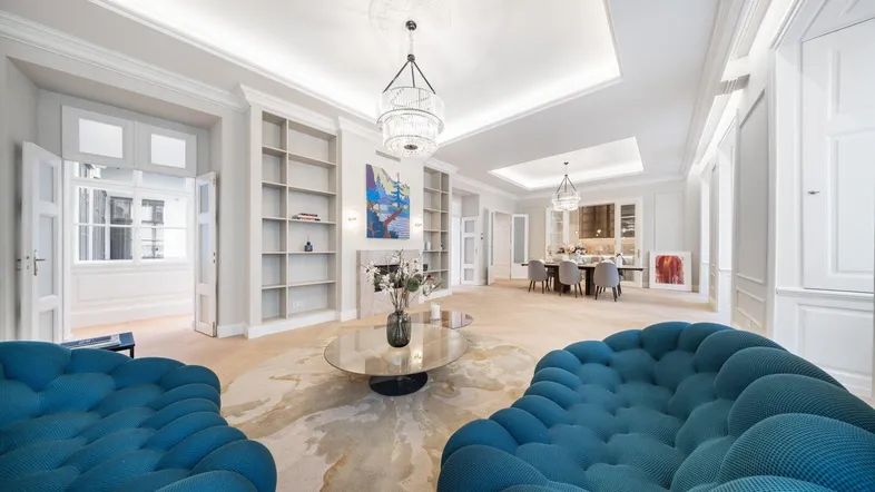 Elegantes Wohn- und Esszimmer mit modernen blauen Sofas, Kamin und integrierten Bücherregalen.