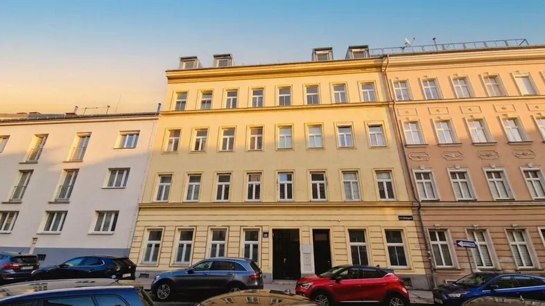 Historisches Mehrfamilienhaus mit klassischer Fassade und vielen Fenstern an einer Stadtstraße.