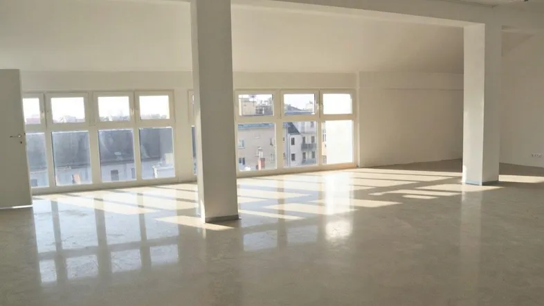 Geräumiger, heller Büroraum mit großen Fenstern, die viel Tageslicht hereinlassen und einer offenen Gestaltung.