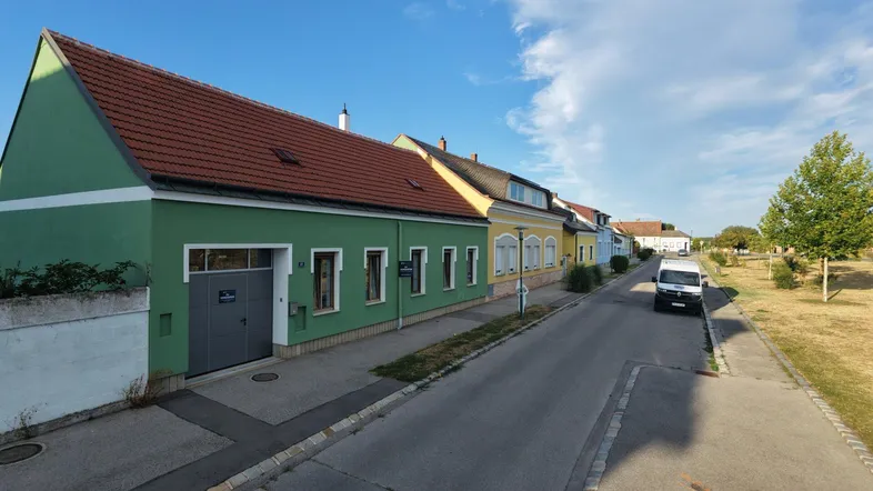Eine Reihe von Häusern entlang einer Straße mit grünen und gelben Fassaden unter blauem Himmel.