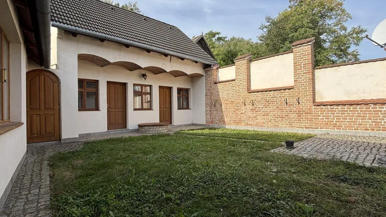 Sonniger Innenhof mit Rasen, Ziegelmauer und traditioneller Architektur des Hauses.