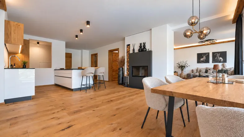 Geräumiger offener Wohn- und Essbereich mit moderner Küche, Kamin und Holzboden.