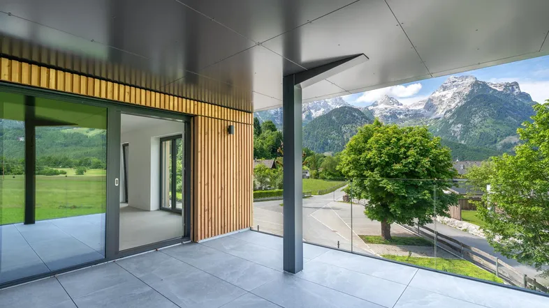Moderner Balkon mit Fliesenboden, Holzverkleidung und atemberaubendem Bergblick.