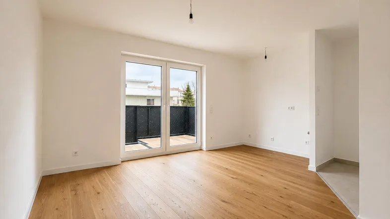 Helles Zimmer mit Holzboden und Zugang zu einem Balkon, ideal für einen Wohnbereich.