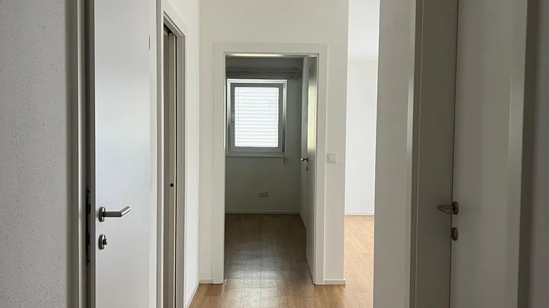 Heller Flur mit Holzboden und mehreren Türen, der zu weiteren Räumen führt.