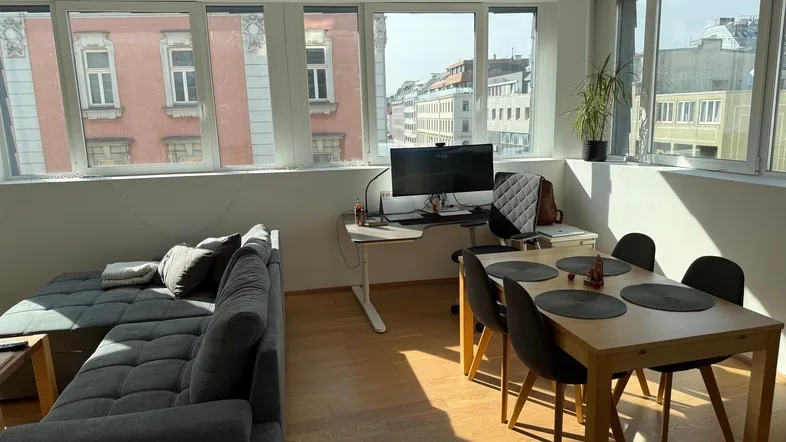 Helles Wohn- und Esszimmer mit urbanem Ausblick, Holzboden und moderner Einrichtung.