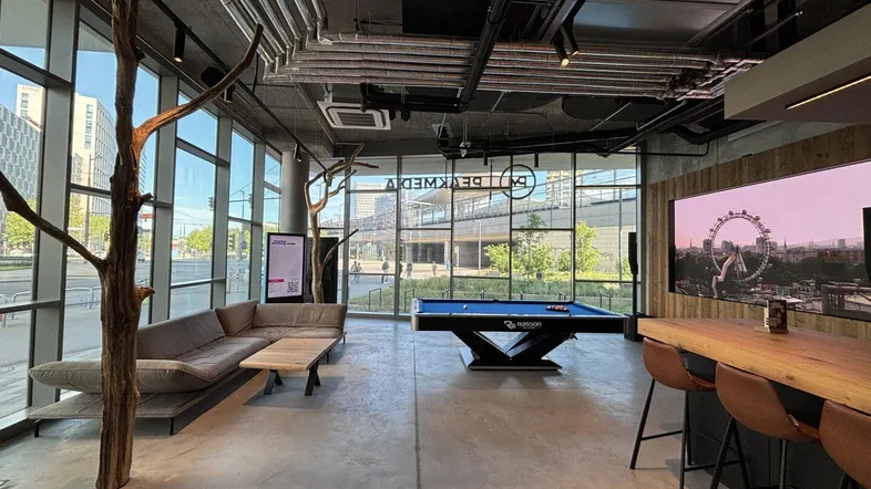 Moderner Loungebereich mit Billardtisch, großen Fenstern und bequemen Sofas, ideal für entspannte Stunden.