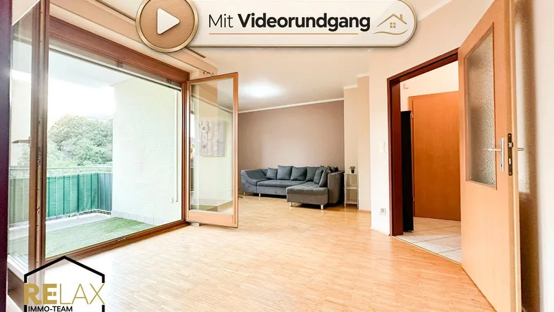 Helles Wohnzimmer mit Holzparkett, großem Sofa und Zugang zu einem sonnigen Balkon.
