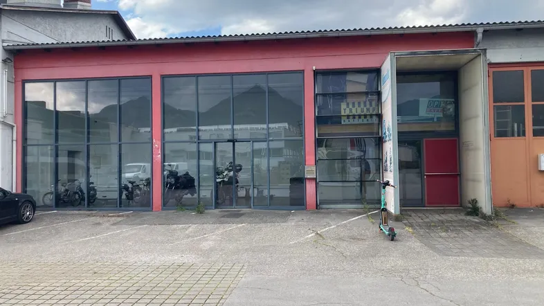 Die moderne Geschäftsfassade verfügt über große Glasfenster und einen Eingangsbereich mit Parkplätzen davor.