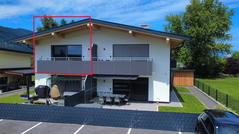 Modernes Mehrfamilienhaus mit Balkon, Terrasse und gepflegtem Gartenbereich in grüner Umgebung.