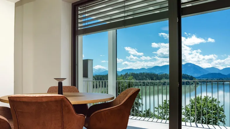 Heller Essbereich mit modernem Tisch und Stühlen, bietet einen atemberaubenden Blick auf den See und die Berge.