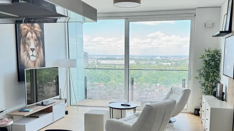 Modernes Wohnzimmer mit großen Fenstern, Stadtblick und bequemen Sesseln.