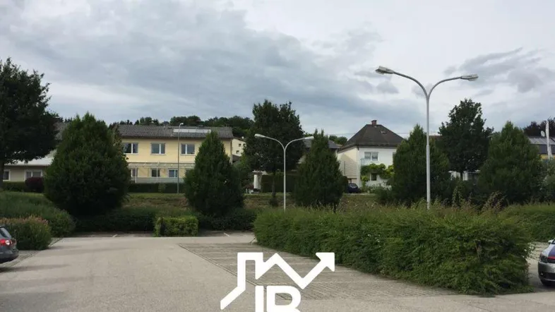 Außenansicht mit Parkplätzen, Bäumen und Wohngebäuden in einer ruhigen Wohngegend.