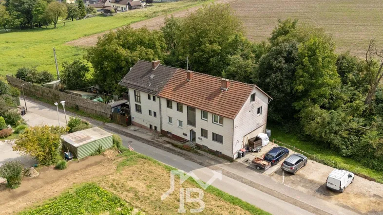 Luftaufnahme des Mehrfamilienhauses mit umliegenden Feldern und ländlicher Umgebung.