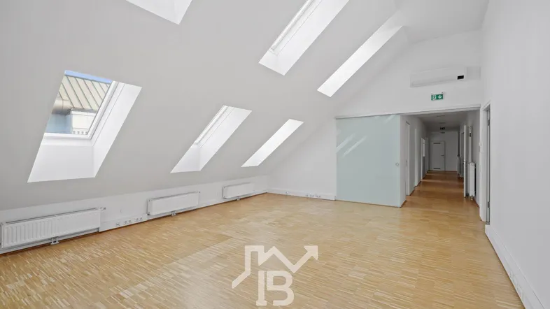 Geräumiger, heller Raum mit Dachschrägen, mehreren Dachfenstern und Parkettboden, ideal für Wohn- oder Büronutzung.