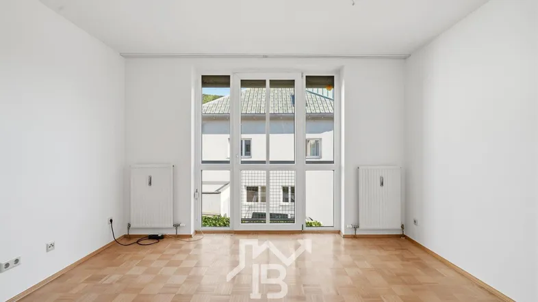Helles, unmöbliertes Zimmer mit Parkettboden und großen Fenstern, die viel Tageslicht hereinlassen.