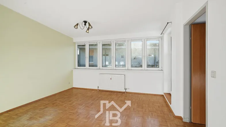 Helles Wohnzimmer mit Parkettboden und großen Fenstern, bereit zur individuellen Gestaltung.