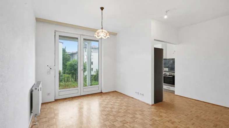 Helles Wohnzimmer mit Parkettboden und Zugang zu einem Balkon oder Gartenbereich.