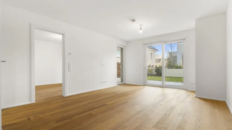 Helles Wohnzimmer mit Parkettboden und Zugang zu Terrasse und Garten.