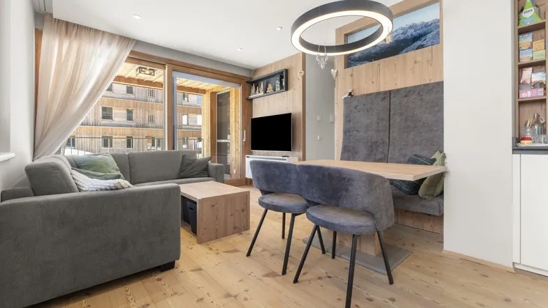 Heller Wohnbereich mit Holzboden, bequemer Couch und Zugang zum Balkon.