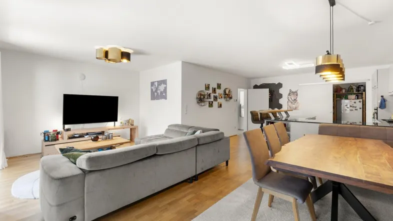 Heller offener Wohn- und Essbereich mit modernem Sofa, Esstisch und Blick zur Küche.
