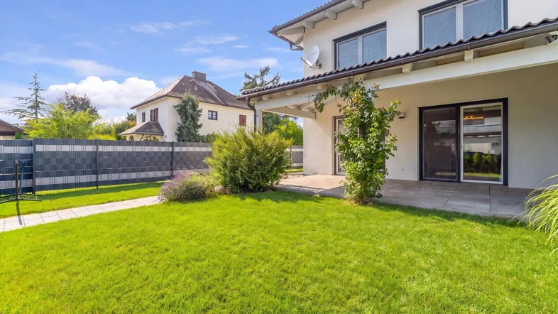Gepflegter Gartenbereich mit Rasenfläche und Zugang zur überdachten Terrasse des Hauses.